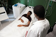 © ABCreative - African girl rests in her hospital bed, an African patient stands quietly nearb.