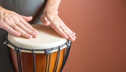 Hands playing a drum with a warm background.