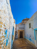 Fototapeta Uliczki - One of the streets of the old Tunisian cities, where the distinctive Tunisian Arab architecture is evident, with the beautiful colours of its doors and windows and its narrow streets.