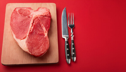 Juicy raw steak and cutlery on red background. Fresh uncooked meat. Cooking and culinary