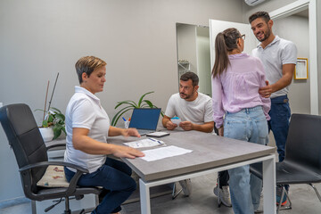 Female doctor consulting with wife and husband, offering medical advices to a young couple in office