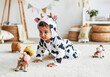 © EvgeniiaFreeman - Adorable baby in cow costume crawling on soft carpet in nursery
