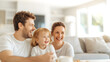 © Korakrich - A happy family gather in a cozy living room, bathed in soft morning light streaming to large windows. Laughter fills the air as they enjoy peaceful, serene moments of warmth, joy, and togetherness.