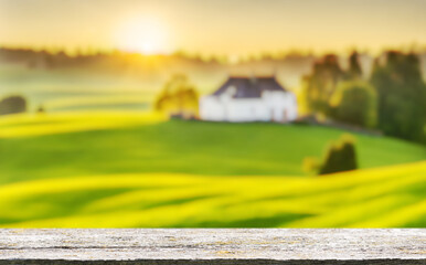 Fototapete - An empty wooden table in the foreground with a sunny meadow in the background