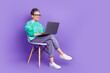 © deagreez - Full size photo of pretty retired female sit chair netbook wear trendy green outfit isolated on violet color background
