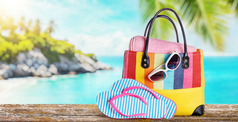 Poster - A beach bag with towels, sunglasses, and flip flops placed on a table