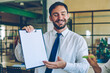 © BullRun - Successful man in formal wear holding folder with mockup area for advertising text while standing near desktop in office, male and female colleagues collaborating togetherness on new business project