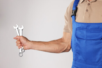 Poster - Auto mechanic with wrenches on light grey background, closeup