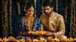 © Art Resources - Portrait of a young Indian woman in a royal blue lehenga and a young Indian man in a gold sherwani, both together holding a single thali with diyas, indoor Diwali backdrop with a vibrant rangoli