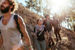 © Marko Geber - Group of friends hiking through forest trail with walking poles