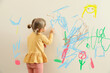 © New Africa - Little child drawing on white wall, back view