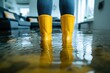 © Minerva Studio - Woman wearing rubber boots standing on flooded floor at home