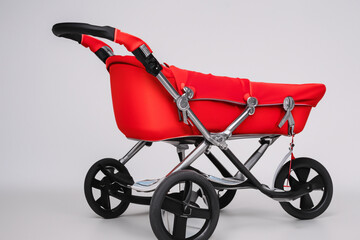 Gray and red stroller on gray . white child carriage concept. baby stands on gray next to a stroller. a baby stands on a gray next to lifestyle a stroller.