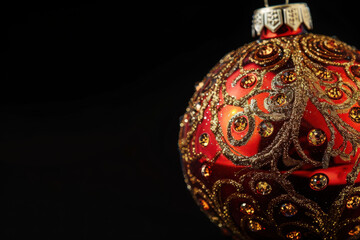 close up horizontal detailed image of a shiny glittery decorative christmas ball over a dark background, copy space