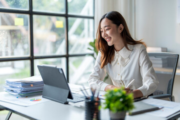 Wall Mural - asian businesswoman working with laptop computer and taking notes in modern office