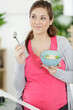 © auremar - beautiful pregnant woman eating with lust cereals on breakfast