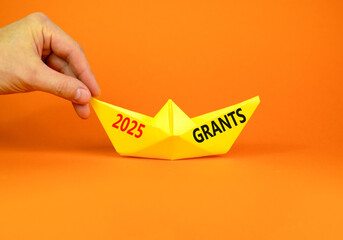 Planning 2025 grants new year symbol. Concept words 2025 Grants on beautiful yellow paper boat. Beautiful orange paper background. Businessmen hand. Business 2025 grants new year concept. Copy space.