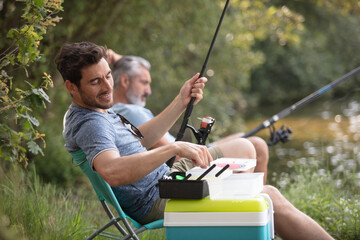 Wall Mural - two male friends fishing together on the lake