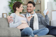 © auremar - cheerful pregnant couple playing together with baby shoes at home