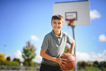 sporty boy wear grey sports clothes play basketball game on playground court