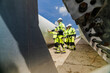© ultramansk - engineers in high visibility safety gear conduct a detailed inspection of a wind turbine blade at a construction site. The massive blade lays on the ground, highlighting renewable energy technology.