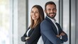 © Adi - Successful happy businessman and businesswoman standing back to back with arms crossed and smiling at camera, office interior. Partnership concept. with copy space
