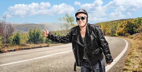 Wall Mural - Mature hitchhiker in a black leather jacket and helmet