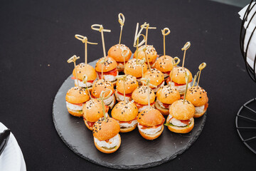 Wall Mural - There is a decorative plate filled with an assortment of delicious mini hamburgers that are neatly arranged on toothpicks, beautifully displayed on a table for everyone to enjoy