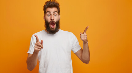 Wall Mural - Portrait of astonished young bearded man wearing white t-shirt standing with open mouth pointing away at advertisement area, copy space, close-up, isolated on orange background