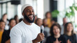 © Катерина Євтехова - A group of diverse professionals engages in a lively team-building exercise in a modern office space. In the foreground, a man in a white shirt and beanie holds a microphone, laugh
