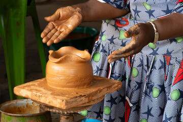 Unrecognizable African woman makes a clay vase with her hands on an artisan potter's wheel