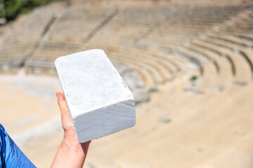 A person is holding a brick in their hand, marble