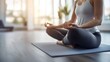 © Anna - The woman sits cross-legged on a yoga mat, practicing meditation in a sunlit studio. She focuses on her breathing, surrounded by greenery, promoting peace and tranquility