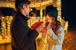 © Zamrznuti tonovi - Amazed girl is looking at gift box in boyfriend's hands on street on christmas.
