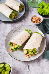 Wall Mural - Beans, cucumber and leaves wrapped in tortilla roll on plate on table vertical view