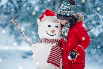 Boy in warm clothing bonding snowman in natural park.