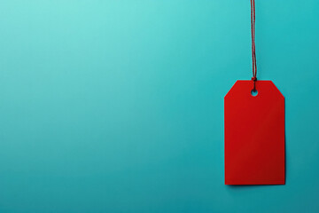 A red tag hangs from a string on a blue background. The tag is red and has a white lettering