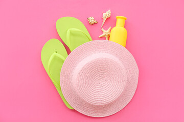 Wall Mural - Pair of green flip flops with hat and sunscreen cream on pink background