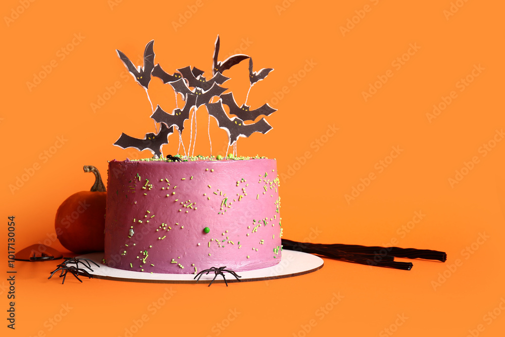 Tasty cake decorated for Halloween on orange background