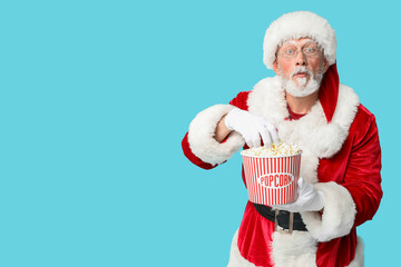 Wall Mural - Santa Claus with bucket of tasty popcorn on blue background