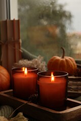 Canvas Print - Burning candles, books and autumn decor on sweater near window, closeup