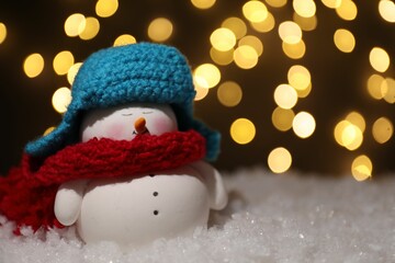 Canvas Print - Cute decorative snowman on artificial snow against blurred lights, closeup. Space for text