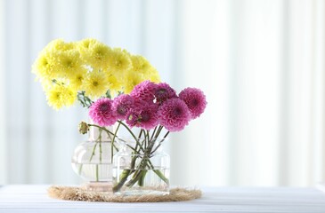 Poster - Beautiful flowers in vases on white wooden table at home. Space for text