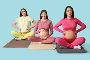 Wall Mural - Beautiful young sporty pregnant women practicing yoga on blue background