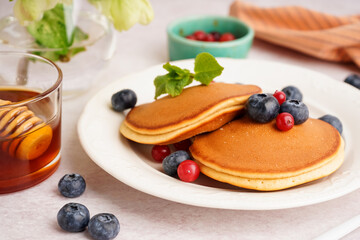 Plate with tasty pancakes and berries on white table