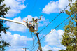 © ungvar - Using utility tower truck, emergency service linemen repair power electrical lines damaged by storm hurricane