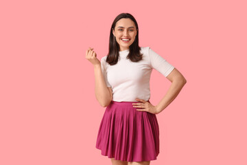 Canvas Print - Smiling young woman showing heart gesture on pink background