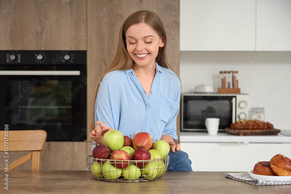 Young woman taking apple from basket in kitchen