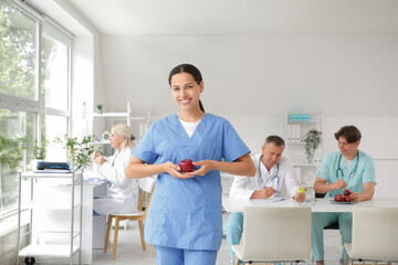 Sticker - Young female doctor with apple in clinic