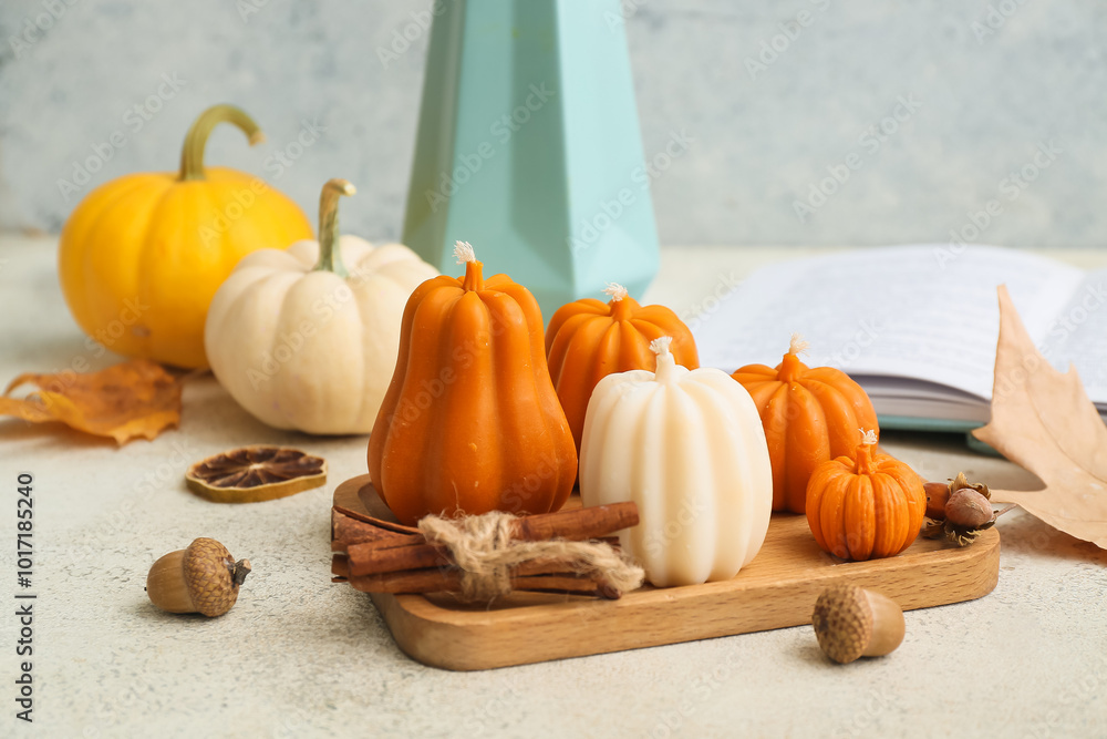 Wooden board with candles, pumpkins and autumn decor on light table